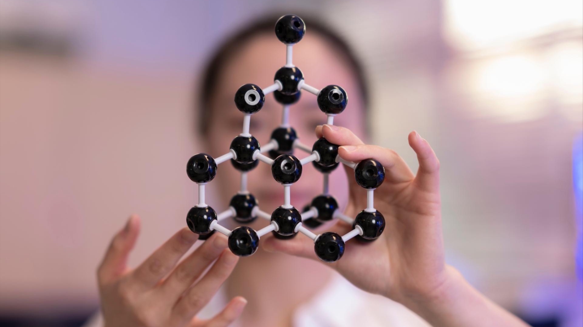 Person holding a black-and-silver molecular model with both hands.
