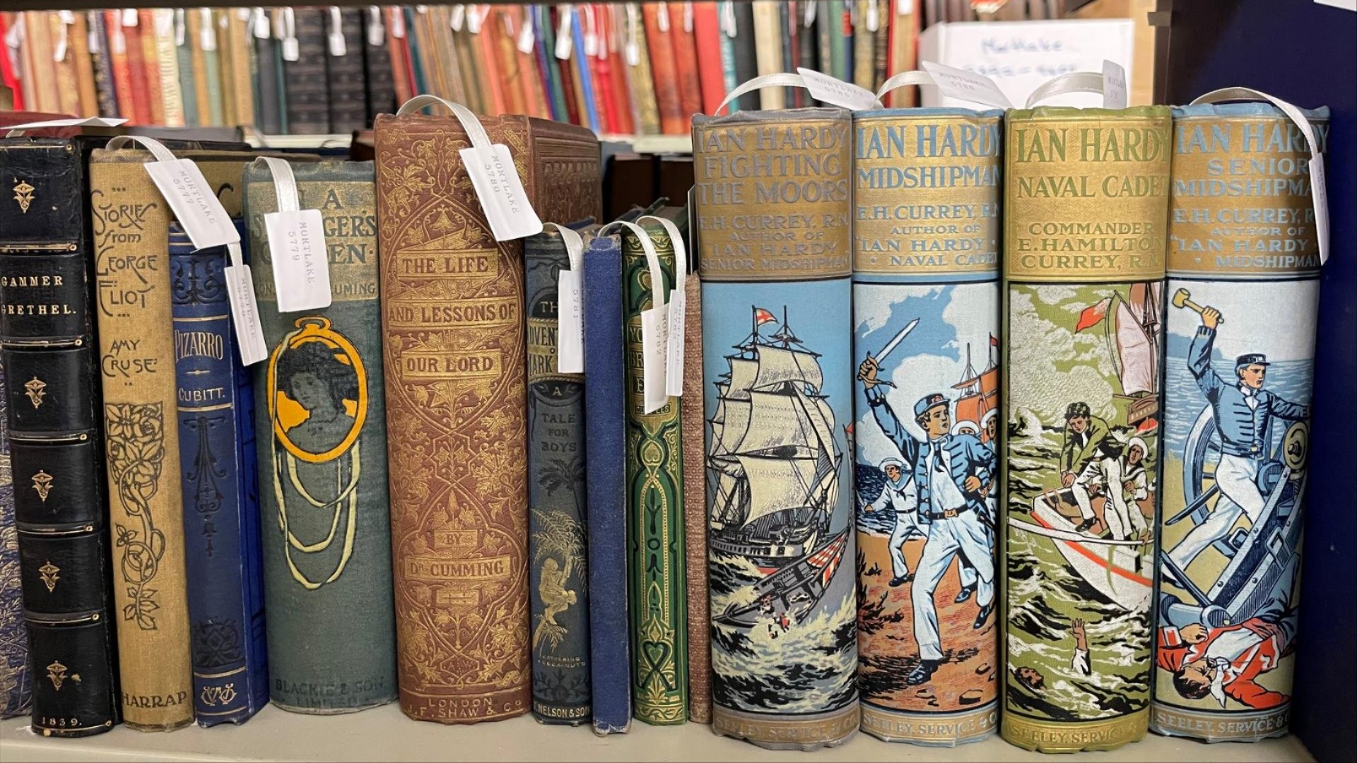 A shelf of vintage books with ornate, colourful covers and decorative spines.