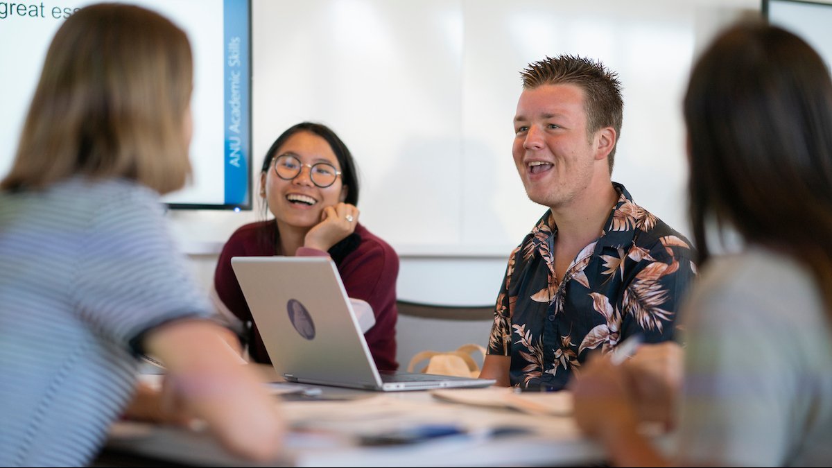 Image of four students in lively conversation sitting at a table.