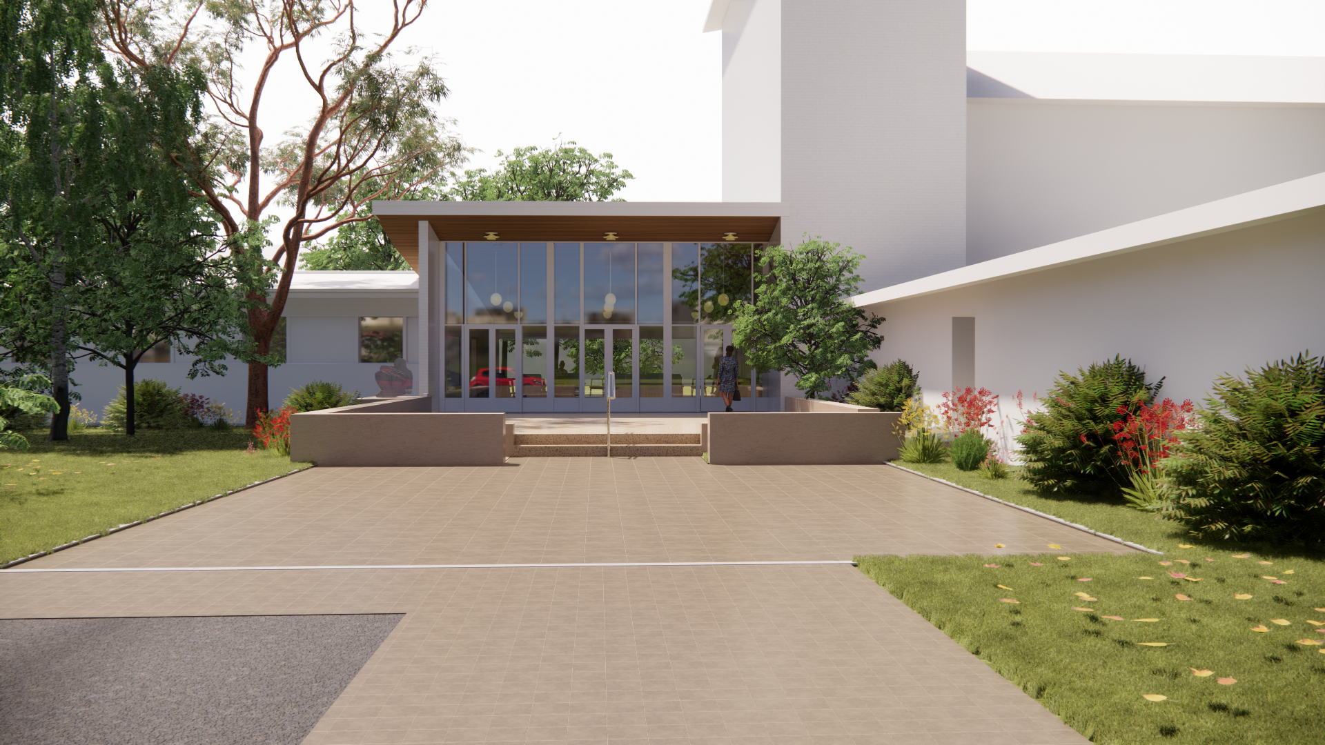 Glass-fronted building entrance with surrounding gardens and trees on a sunny day.