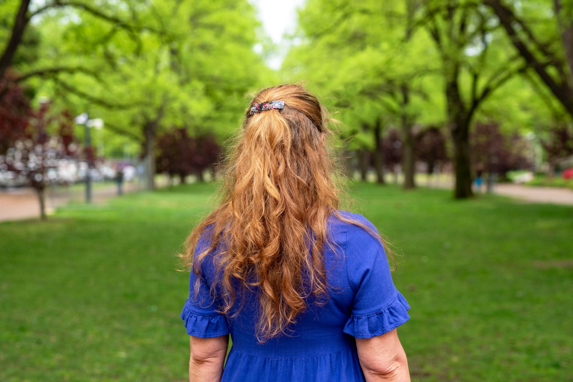 Portrait of a confident woman, Dr Kim Blackmore, looking away into some trees.