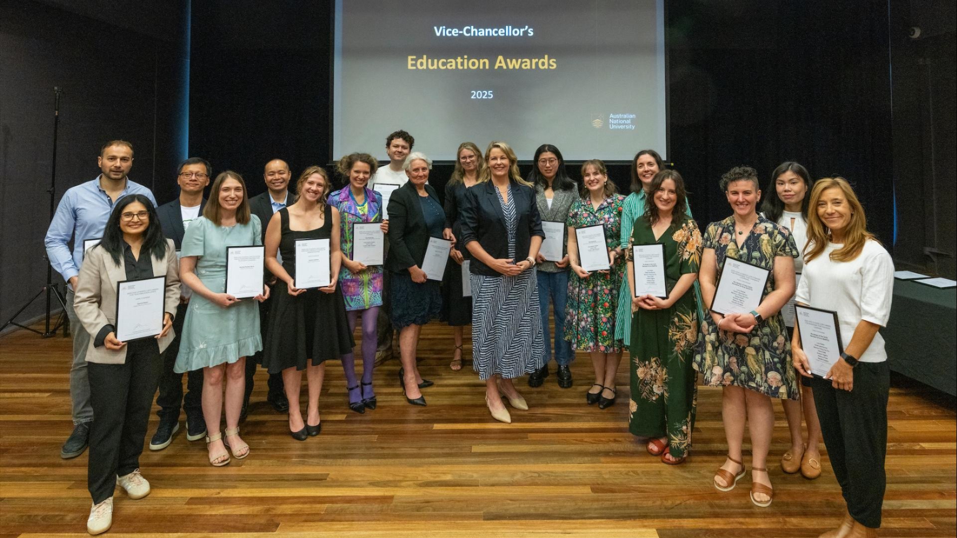 Vice-Chancellor&rsquo;s Education Awards winners stand on a stage holding framed certificates during an awards ceremony, smiling for a group photo with Interim Vice-Chancellor Professor Rebekah Brown.