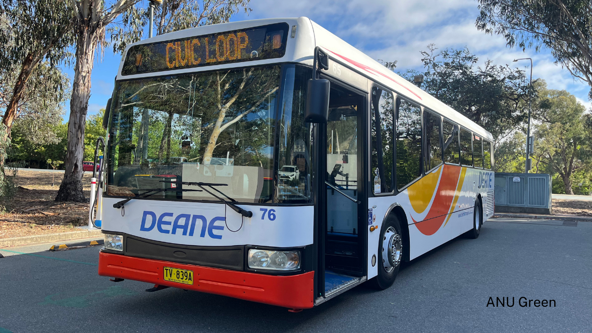 White ��������Green shuttle bus parked on campus roadway.