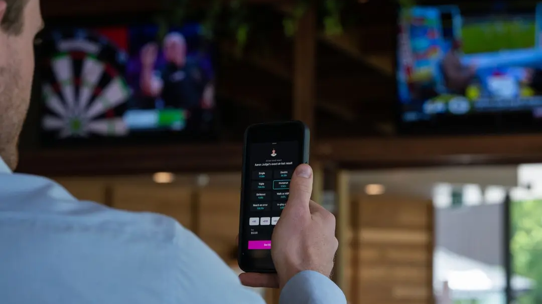 Image of man using phone with gambling app on screen.