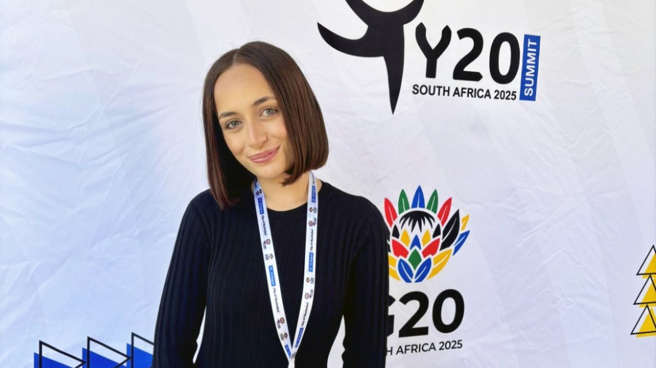 Zyanna Leefe standing in front of a Y20 Summit banner in South Africa.