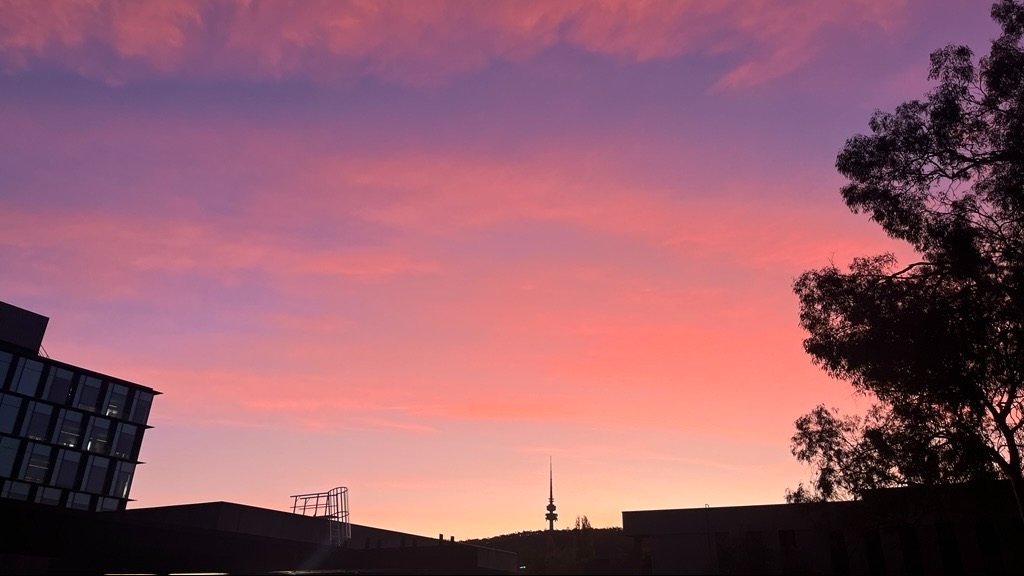 The sky above the ANU Acton Campus bursts with bright pink, fairy floss-like clouds at sunset.