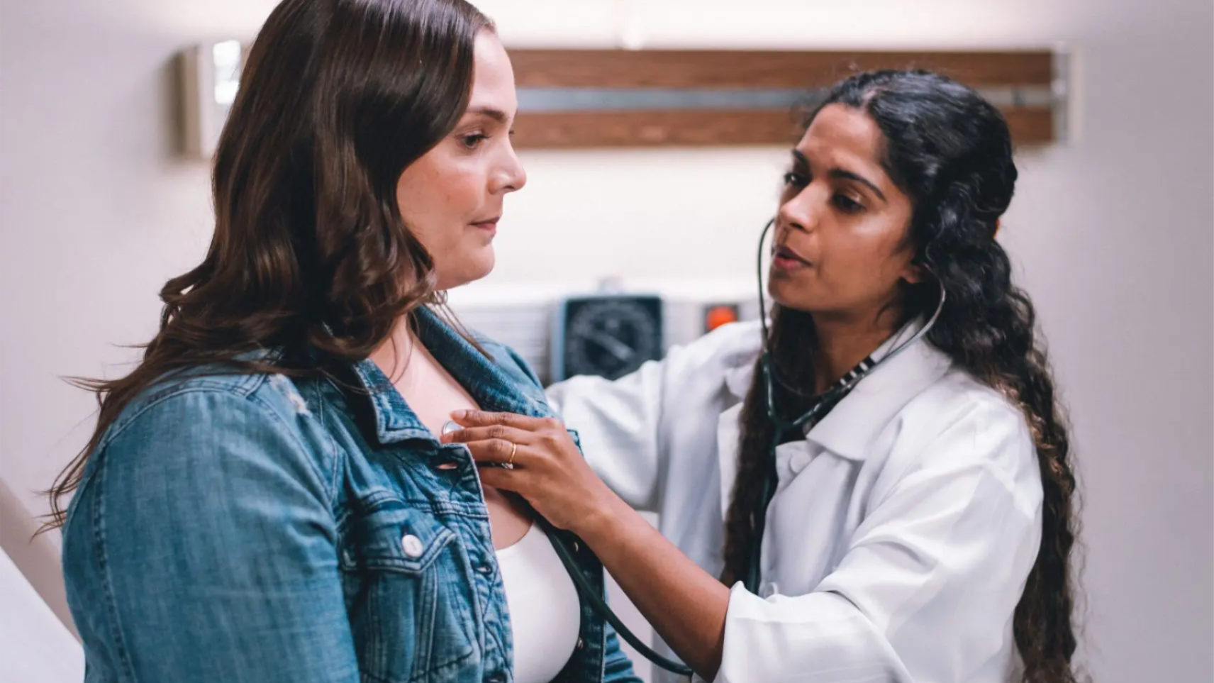 Doctor using a stethoscope to examine a patient in a clinic room.  Is this conversation helpful so far?