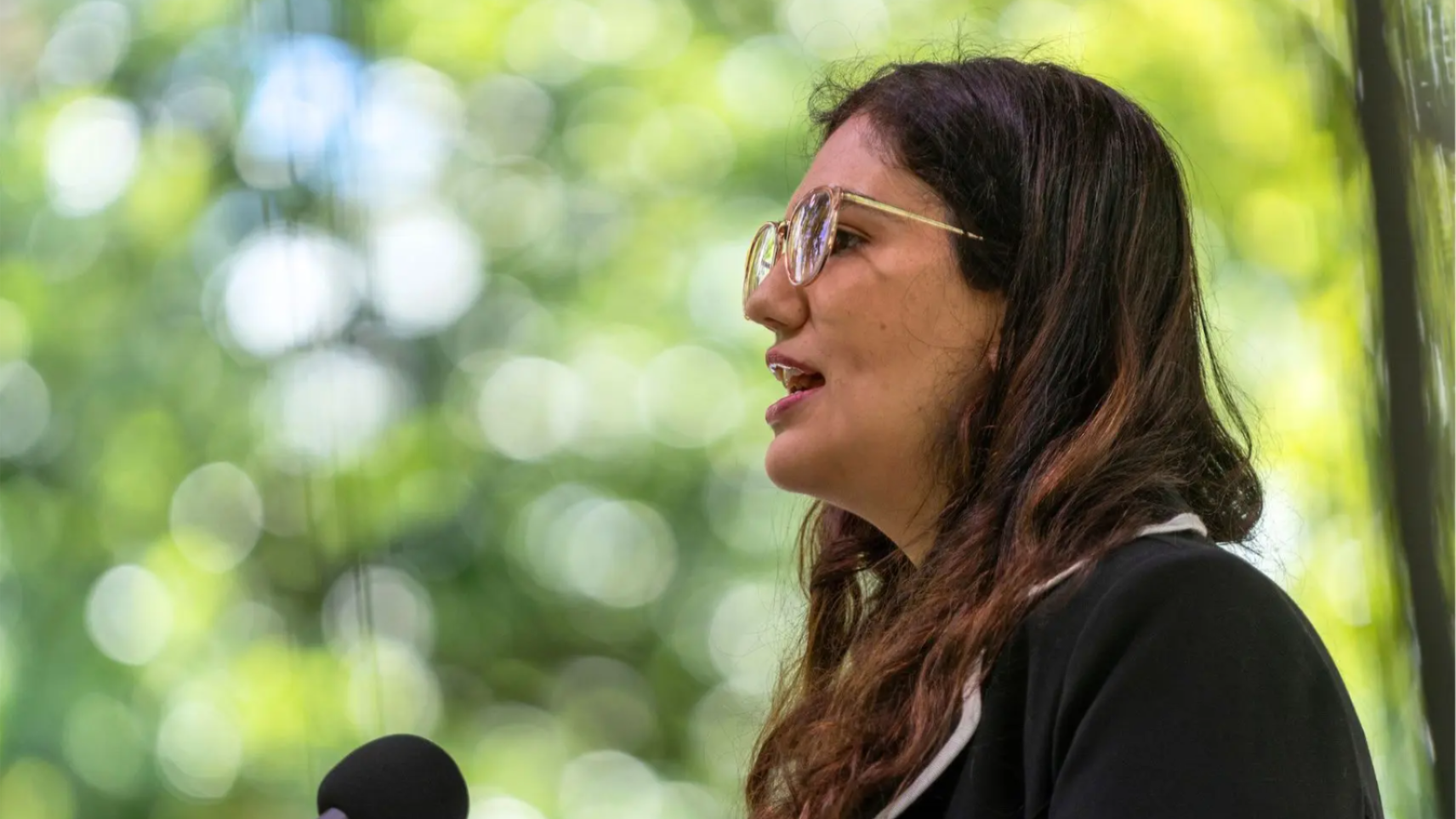 Person arranging clothing on a retail display wall with shelves of clothing and merchandise.