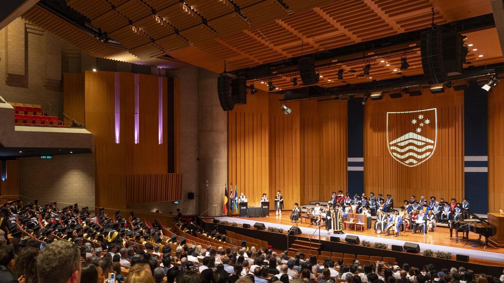 Graduates in academic gowns chat and laugh with family members outdoors at an ��������graduation ceremony