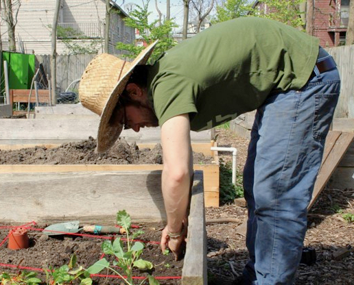 Photo of an urban farmer planting seeds in a community garden. Photo provided by the authors.