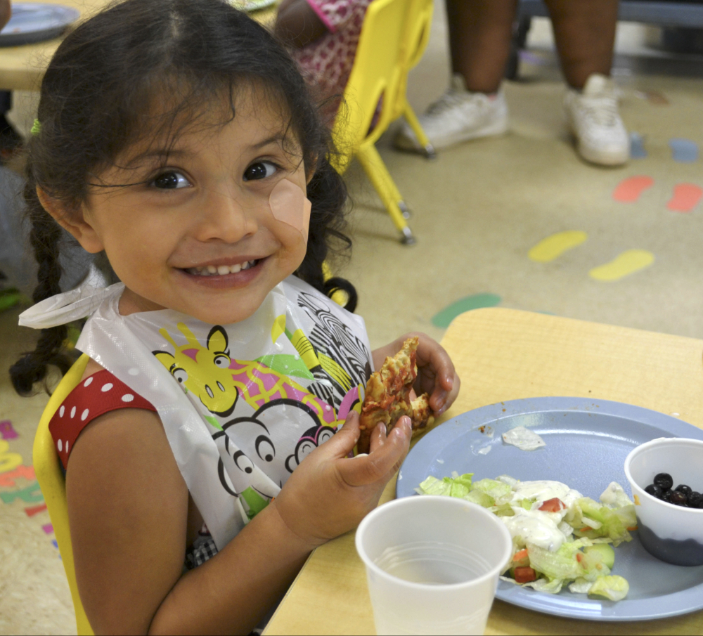 Photo: A girl in preschool eats a lunch of local foods.