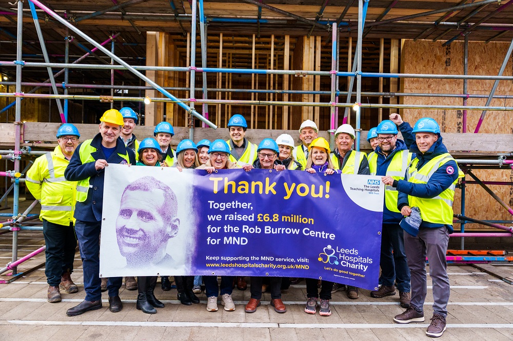 Image of people in hard hats holding poster reading ''Thank you! Together, we raised 6.8 million pounds for the Rob Burrow Centre for MND