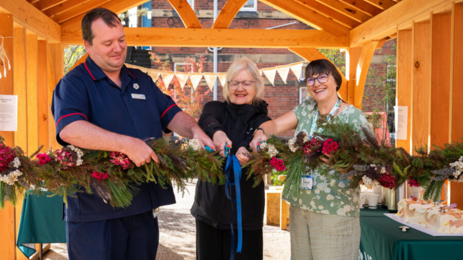 People smiling cutting a ribbon surrounded by flowers