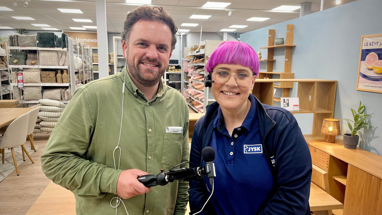 Image of two people smiling, one holding recording equipment