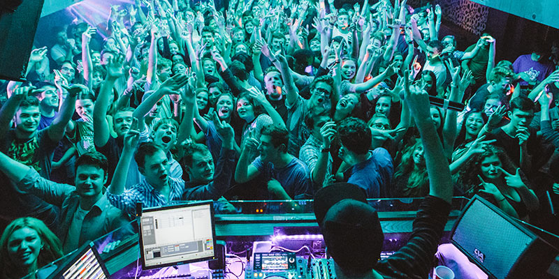 Students dancing in a club in front of a DJ set