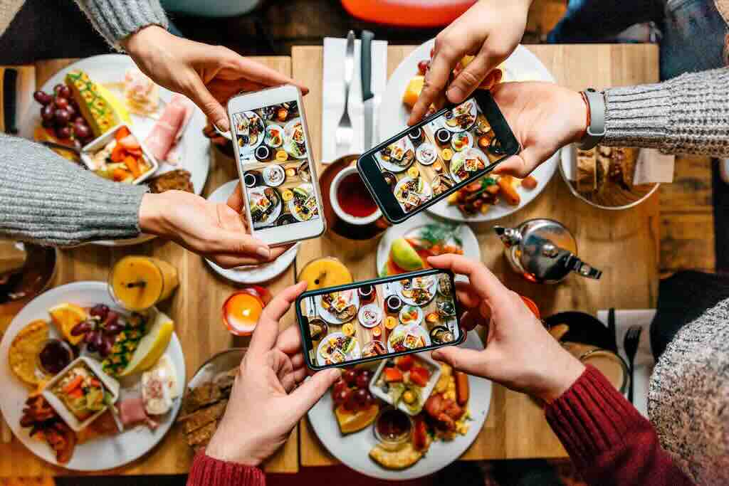 three people taking photos of their meals