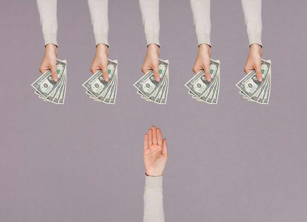 Five sets of hands holding cash out to an empty hand