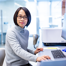 Photo of Jier Huang seated at a desk in front of a computer screen
