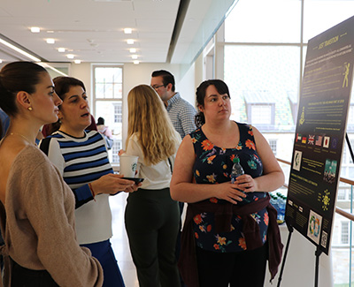 Three people observe a poster presentation.