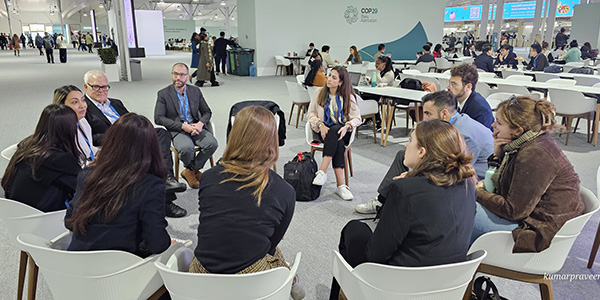 Catherine Goldberg ’16 sits in a group other attendees at COP29.
