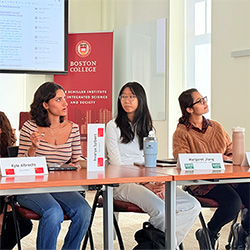 Three student panelists seated at a table, with one student speaking to the audience.