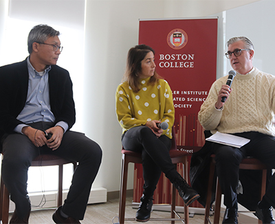 Three panelists seated, with one speaking, during an event.