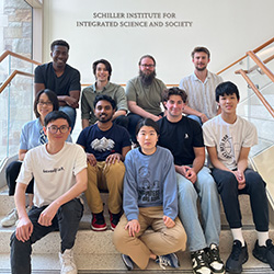 Photo of Jier Huang’s research group; 10 researchers seated on stairs in front of Schiller Institute for Integrated Science and Society sign