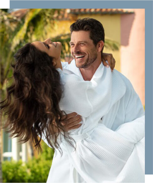 Man wearing a white robe carrying a woman playfully.
