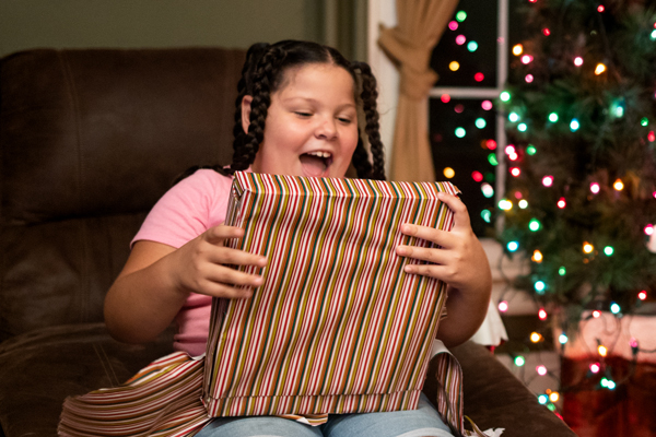 Smiling young girl holding her Angel Tree Christmas gift