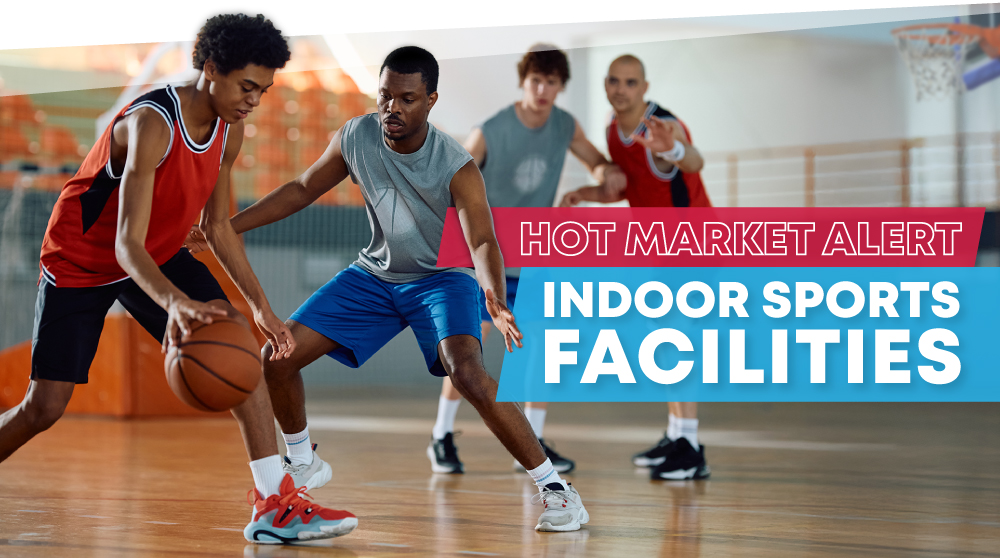 Young men playing indoor basketball with text: Hot Market Alert: Indoor Sports Facilities