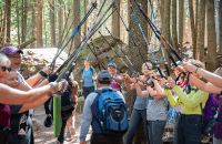 Group of people walking under a canopy of hiking sticks after finishing a hike in the mountains