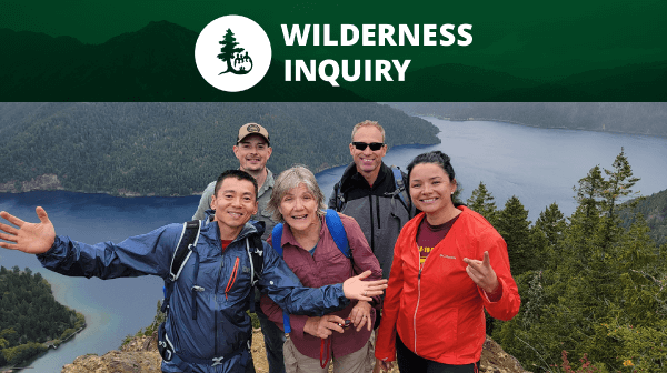 Wilderness Inquiry | Group of 5 people smiling for the camera on top of a mountain