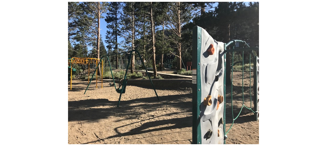 a playground with a climbing wall and swings