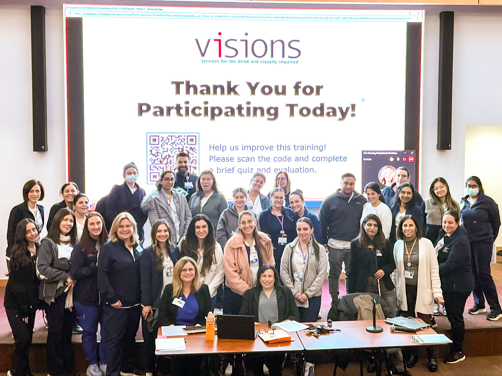 Large group photo of Northwell Health staff standing in front of a large screen playing a VISIONS presentation slide.