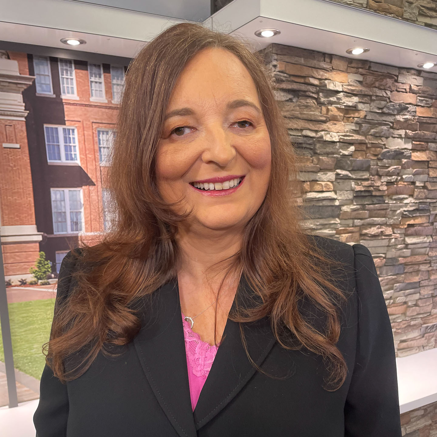 Headshot of Sylvia Stinson-Perez, a medium complexion woman with dark brown hair, wearing a pink shirt and black blazer.