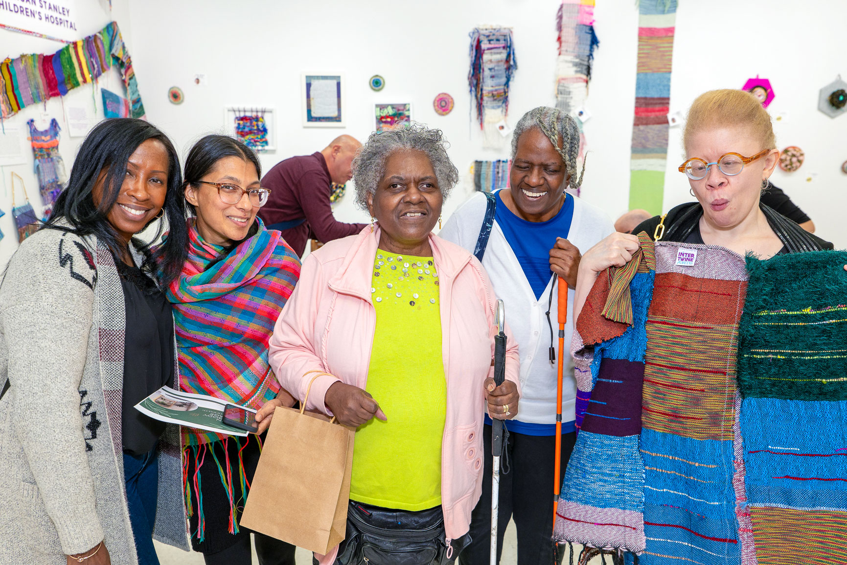 Photo of a group of Older Adult Center staff and participants standing in a gallery of their works, smiling to the camera.