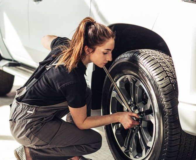 Extend the Life of Your Vehicle at Delaney Chevrolet of Indiana in Indiana, PA | Woman mechanic tightening the wheel lugs on a white car