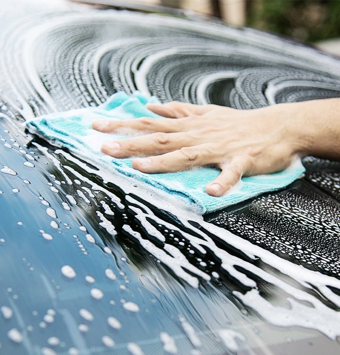 Extend the Life of Your Vehicle at Delaney Chevrolet of Indiana in Indiana, PA | Close up of a person washing their car with soap and microfiber towel