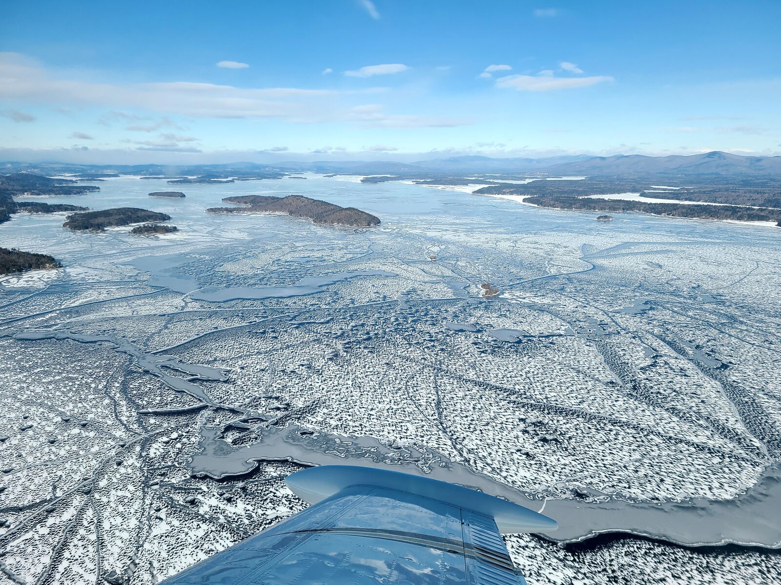 A frozen lake viewed from the air with the wing of an aircraft in the lower portion of the image.