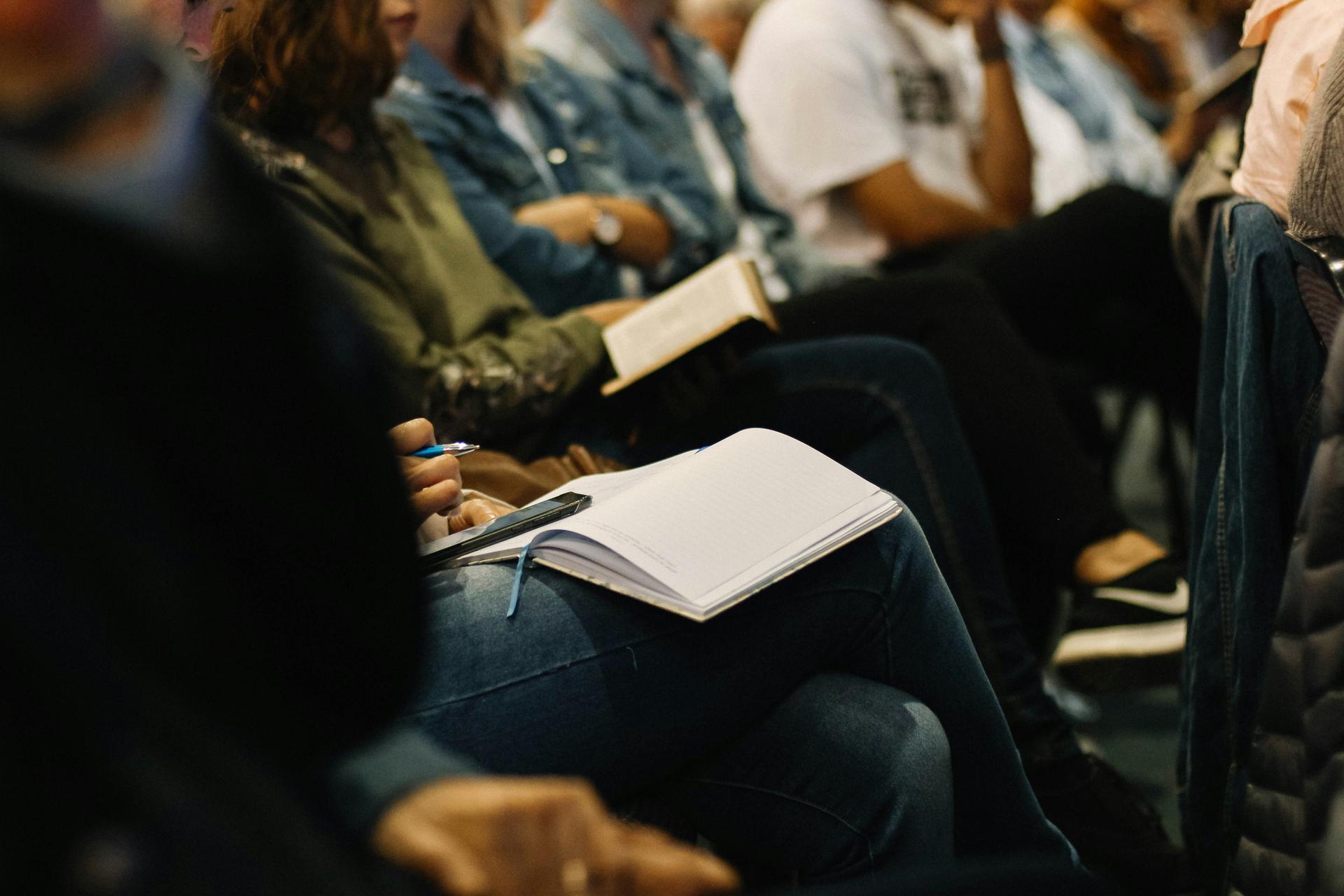 people stitting with notebooks, at an event