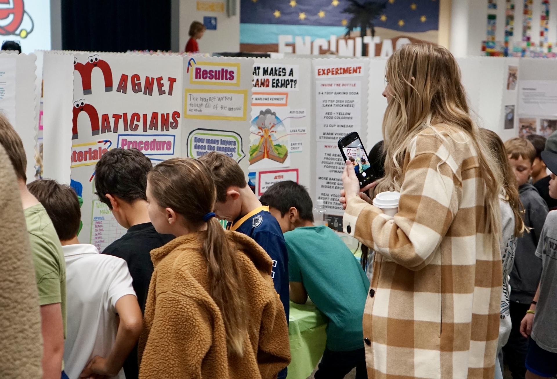 A group of five students and a teacher look at science far project boards.