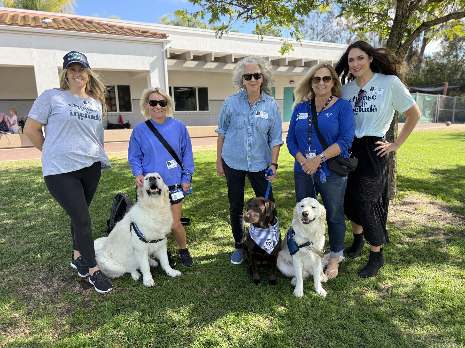 Three students try out basketball wheelchairs on the blacktop.