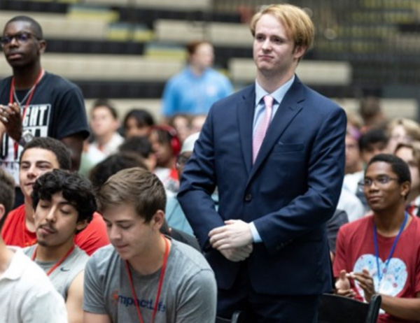 Chase Jackson wearing suit, standing in crowd of Boys State attendees.