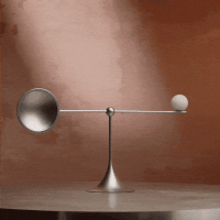 a silver balance with a round object on a round table