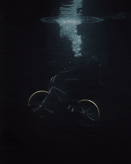 A bike drifts downward through dark water.