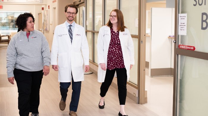 Three people walking in a hospital hallway 