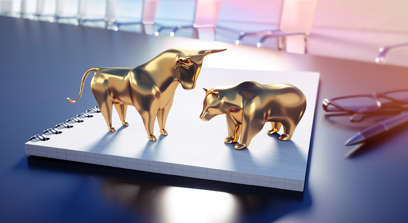 a gold bull and bear figurines on a notepad