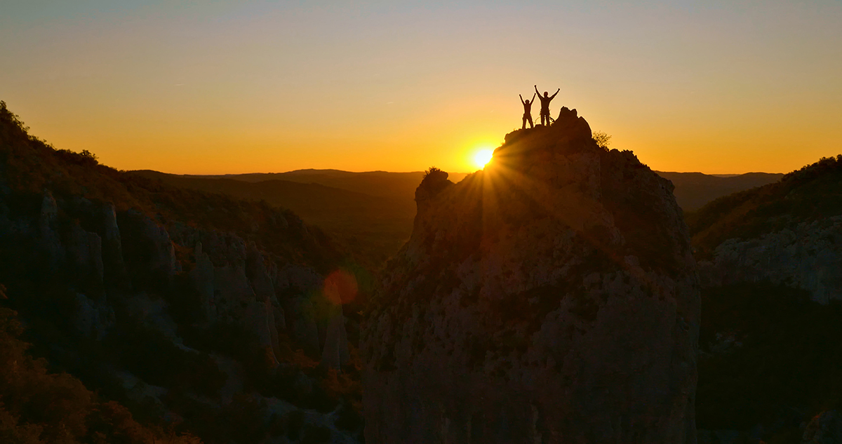 people standing on a mountain with the sun setting behind them