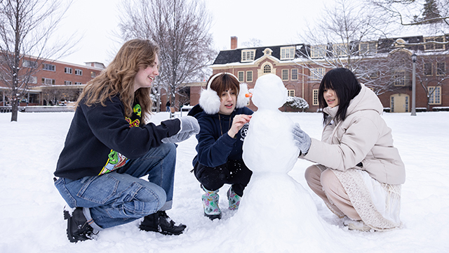 Three students build a snow sculpture on Ankeny Field.