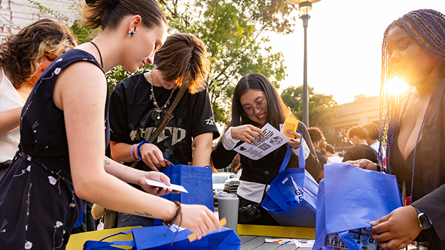 A group of students examine the contents of blue gift bags.